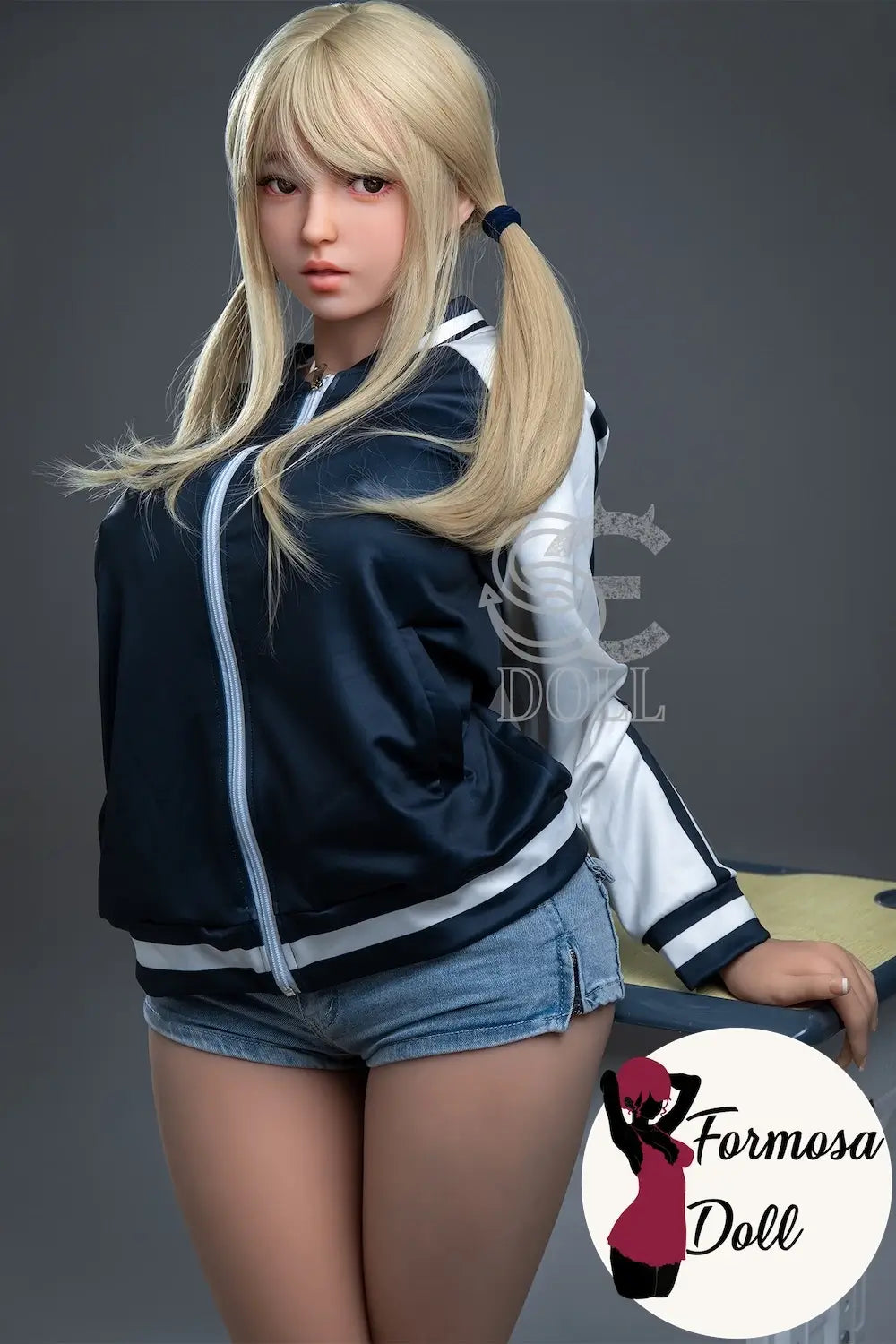 Realistic silicone doll with blonde hair and a black and white jacket on a gray background, featuring the Formosa Doll logo.