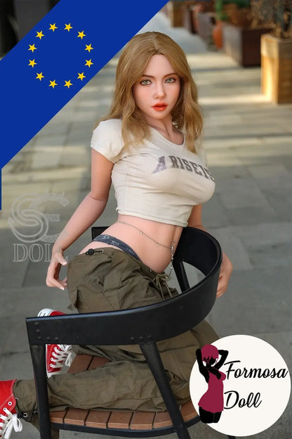 Realistic SEDOLL sex doll sitting on a chair with a blurred background, on the bottom right corner the Formosa Doll logo.